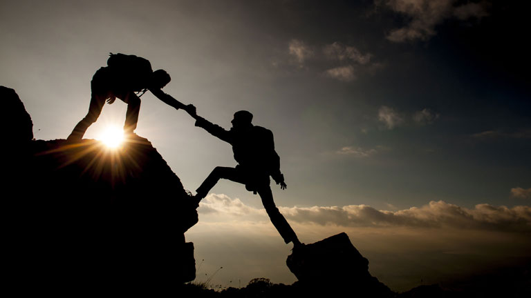 Climbers helping each other summit a peak - Photo credit: crazymedia007